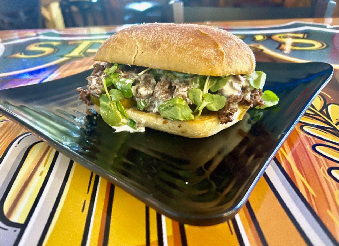 Steak sandwich with melted sharp white cheddar, watercress, caramelized onions, and a horseradish crème fraiche sauce on ciabatta bread