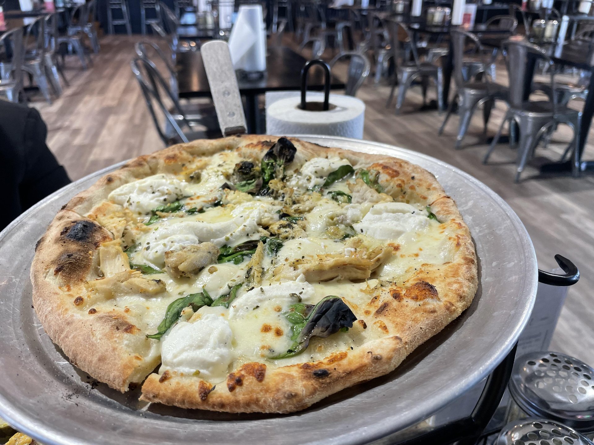Specialty pizza with ricotta and spinach on a silver plate