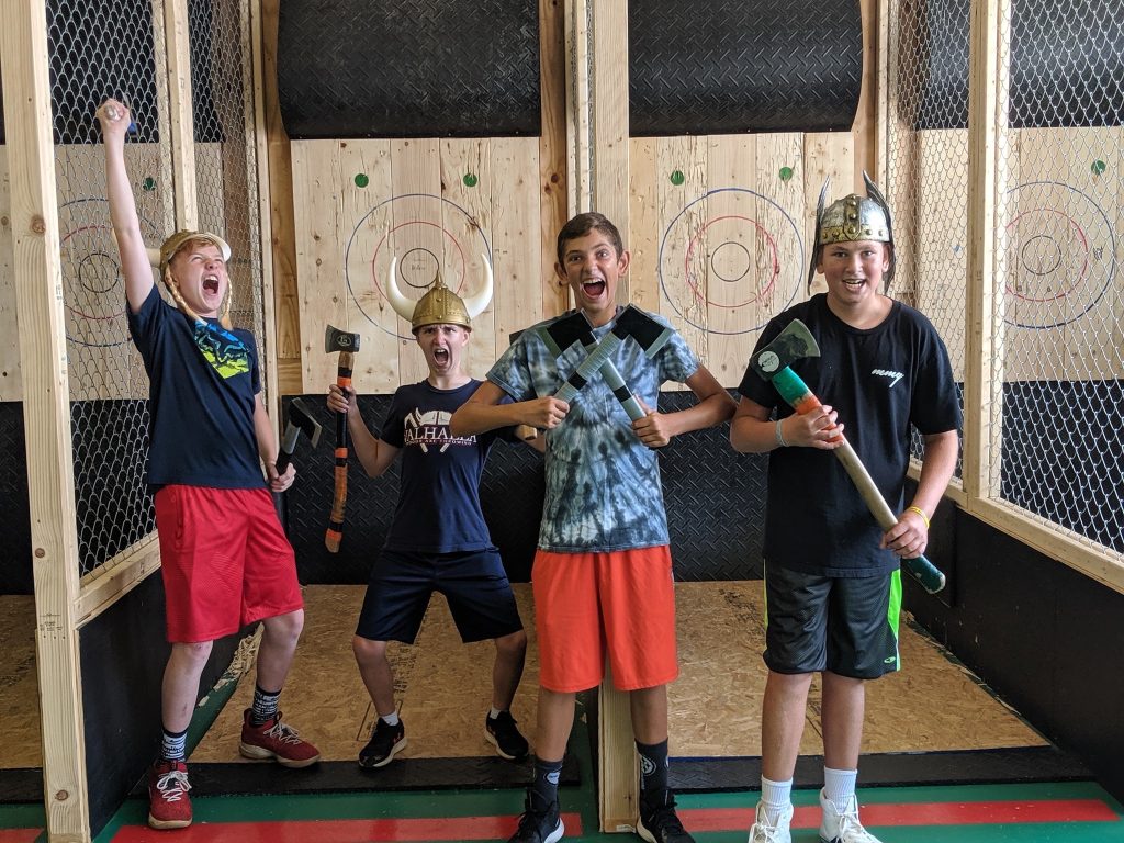 four teens with excited faces and an axe throwing location