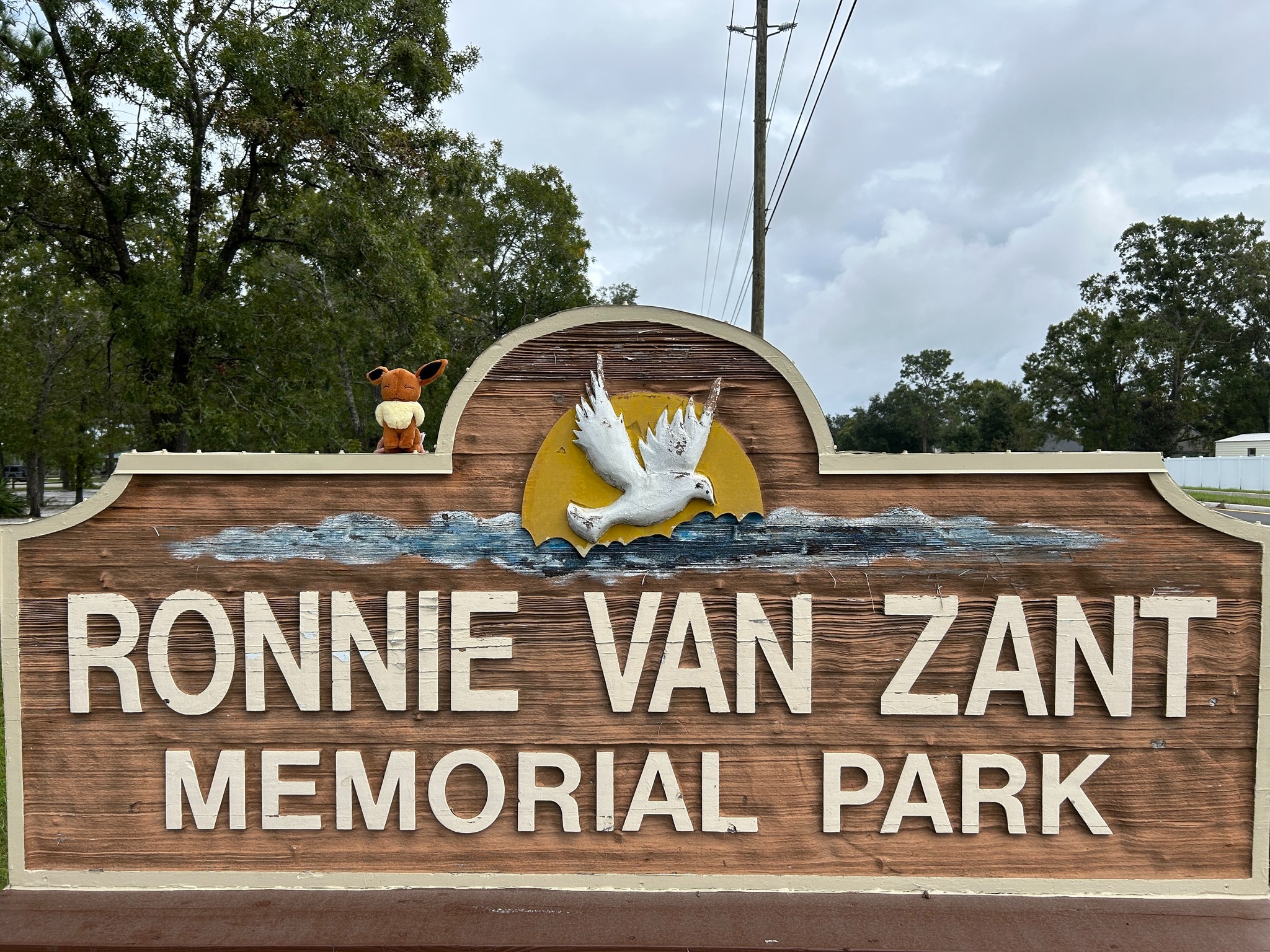 Plush doll sitting on a park entry sign.