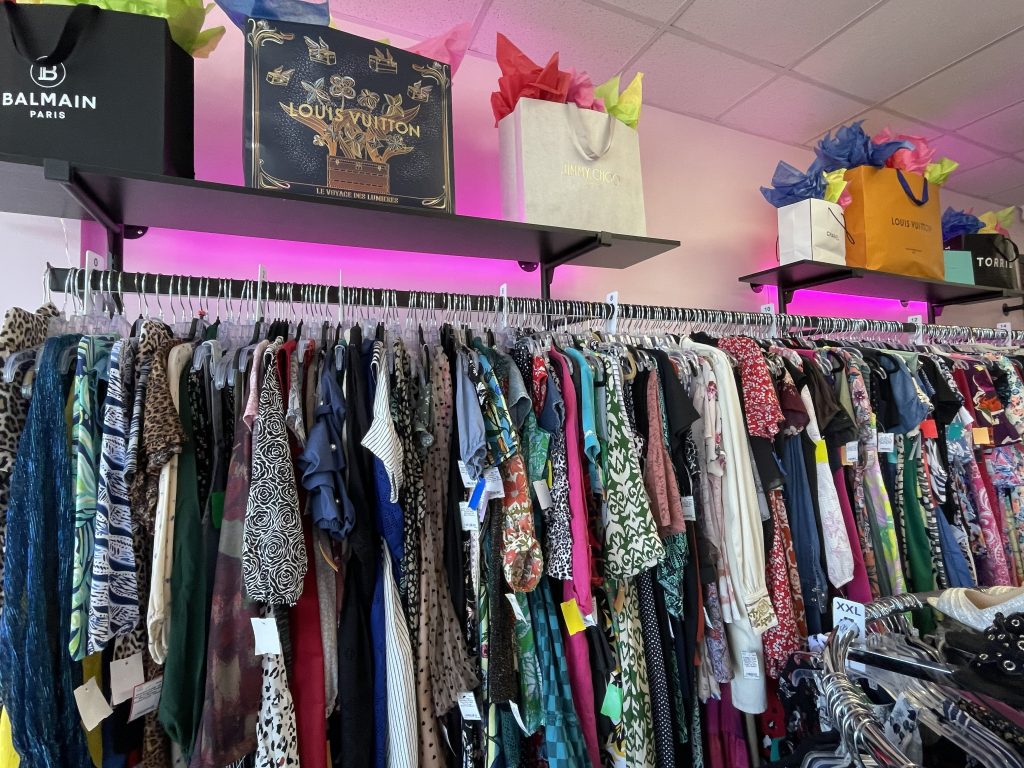 Image of clothing on racks and designer gift bags on top of the displays